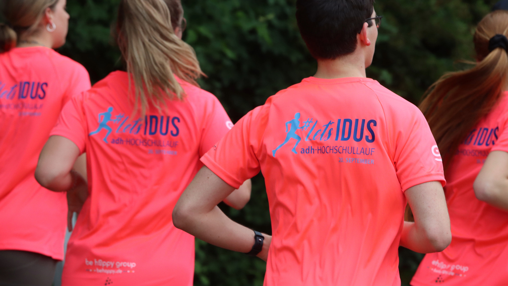 Läuferinnen und Läufer in einem pinken Shirt mit dem Logo des adh-Hochschullaufs